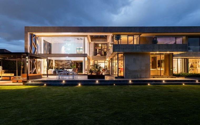Een hedendaagse woning bij avondlicht met verlichte glaspartijen, sfeerbeeld bij de Bouwwerken Verstraeten demo