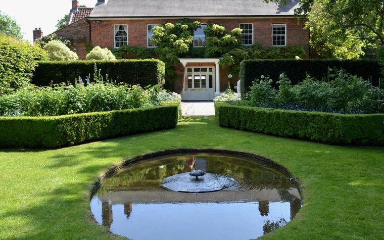 Een formele tuin met geschoren hagen en een spiegelvijver, sfeerbeeld bij de Groenhuis Tuinen demo