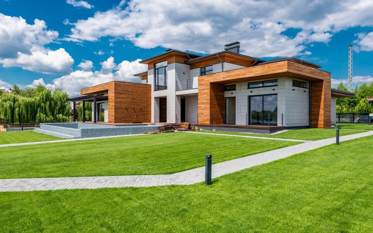 Een moderne architectenwoning met houtgevel en een verzorgd gazon, sfeerbeeld bij de Immo Vandewiele demo