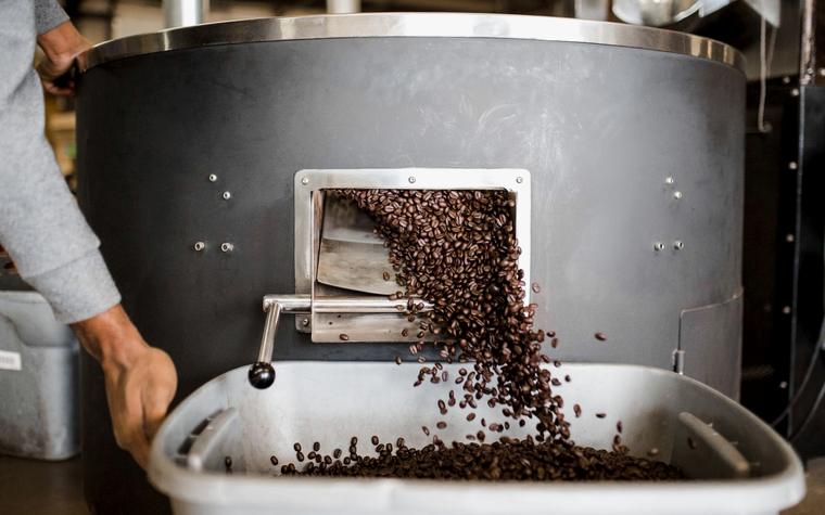 Koffiebonen die uit de brander stromen, sfeerbeeld bij de Meridiaan Koffiebranderij demo