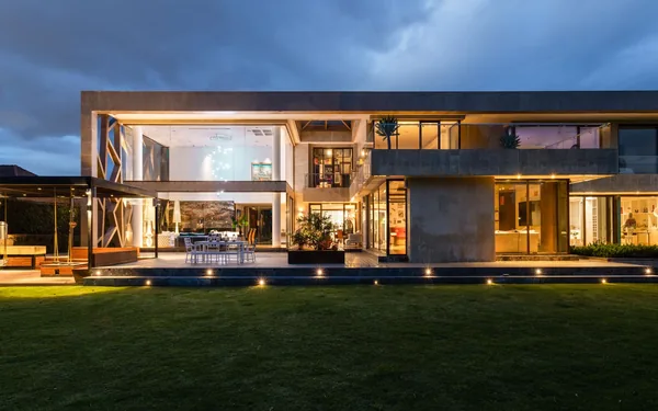 Een hedendaagse woning bij avondlicht met verlichte glaspartijen, sfeerbeeld bij de Bouwwerken Verstraeten demo
