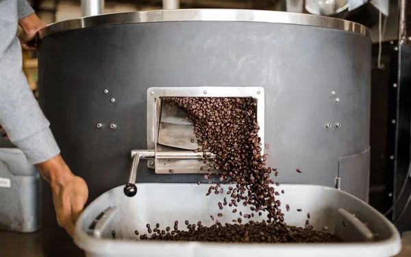 Koffiebonen die uit de brander stromen, sfeerbeeld bij de Meridiaan Koffiebranderij demo