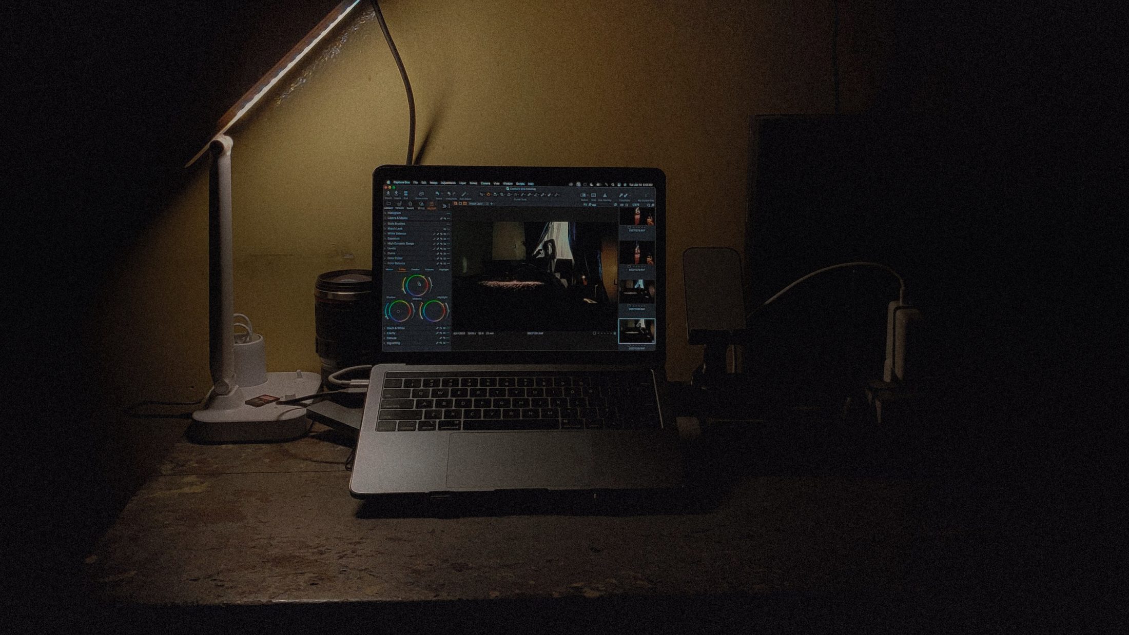 Werkplek bij avondlicht, een laptop onder een bureaulamp in een donkere kamer